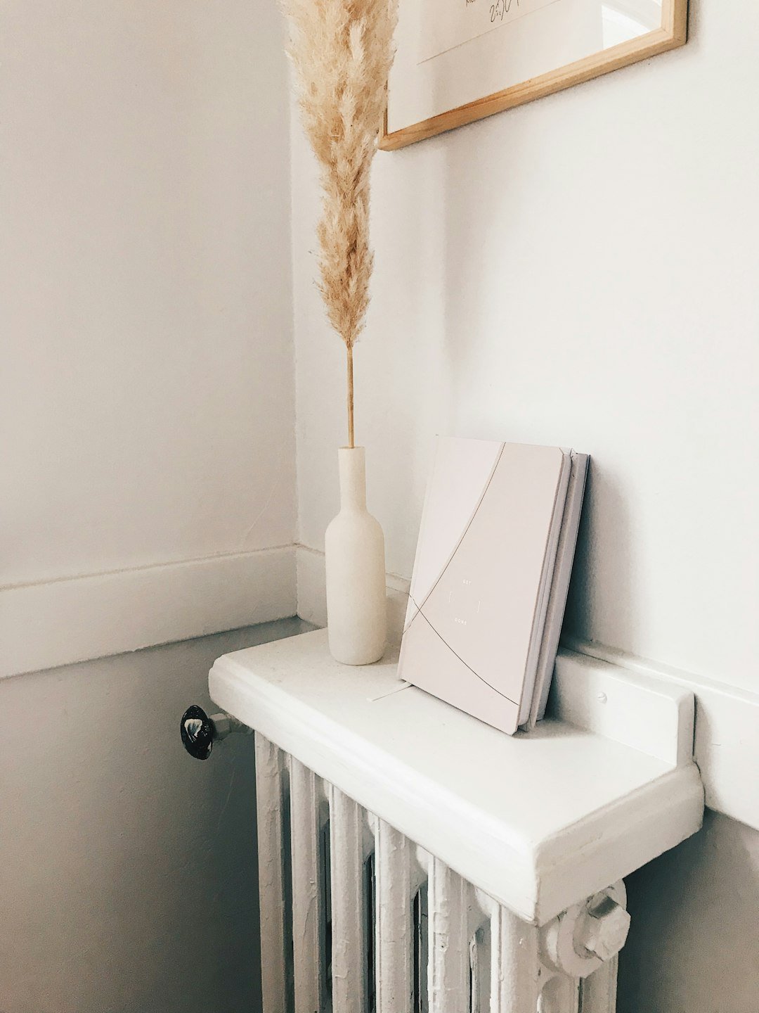 a-white-radiator-with-a-vase-and-a-feather-on-top-of-it-fsamngh-09c